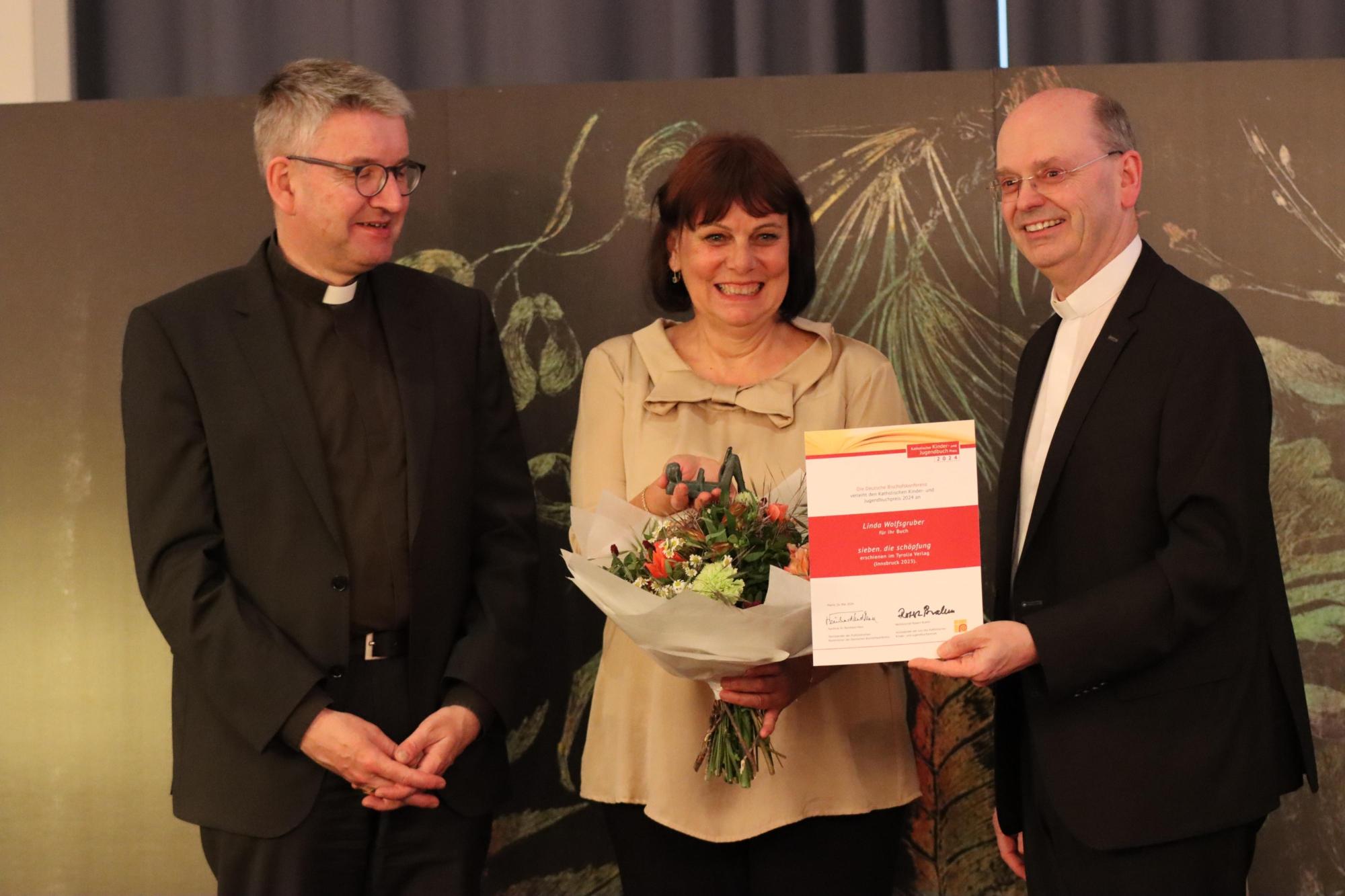 Die Preisträgerin Linda Wolfsgruber mit Bischof Peter Kohlgraf (li.) und dem Jury-Vorsitzenden Weihbischof Robert Brahm aus Trier
