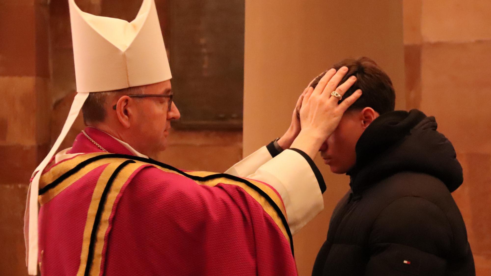 Bischof Peter Kohlgraf legt einem Taufbewerber die Hände auf