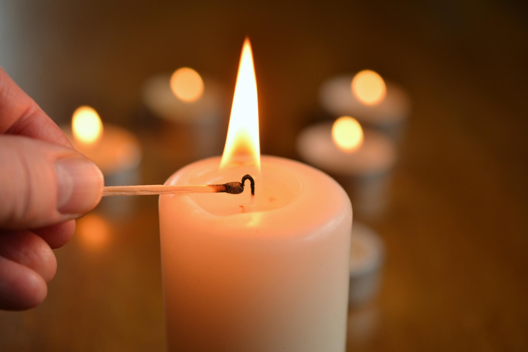 Eine Kerze wird mit einem Streichholz angezündet