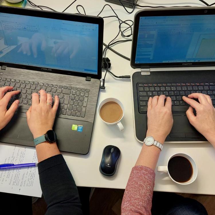Zwei Personen (deren Hände) arbeiten an Laptops