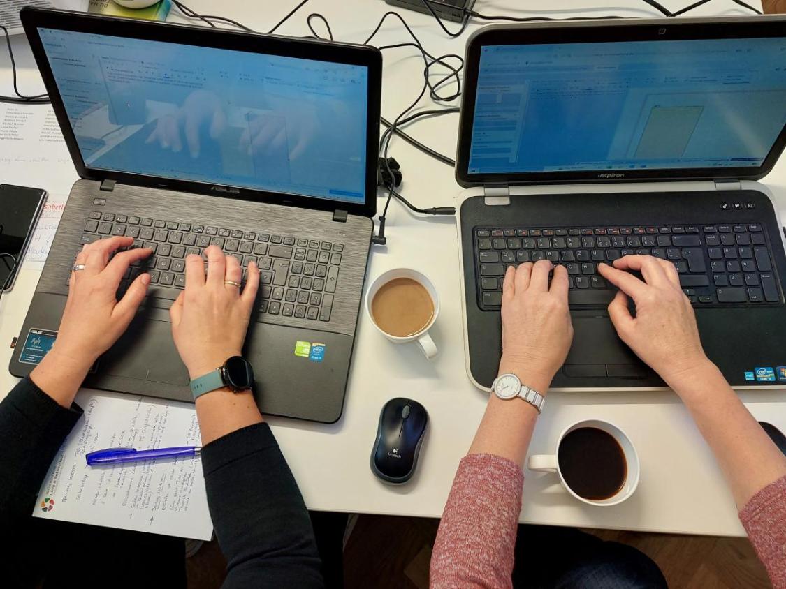 Zwei Personen (deren Hände) arbeiten an Laptops