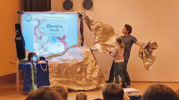 Titelbild Quentin Qualle mit 2 Personen enthüllen das Buchcover