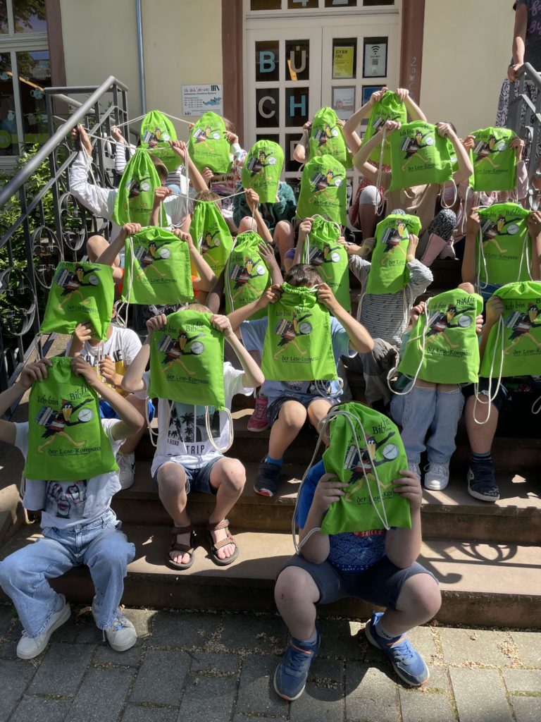 Die Kinder der Hollerbuschschule auf der Treppe der Erbacher Bücherei StSophia mit Rucksack und Kompass (c) Bücherei St. Sophia Erbach/HS