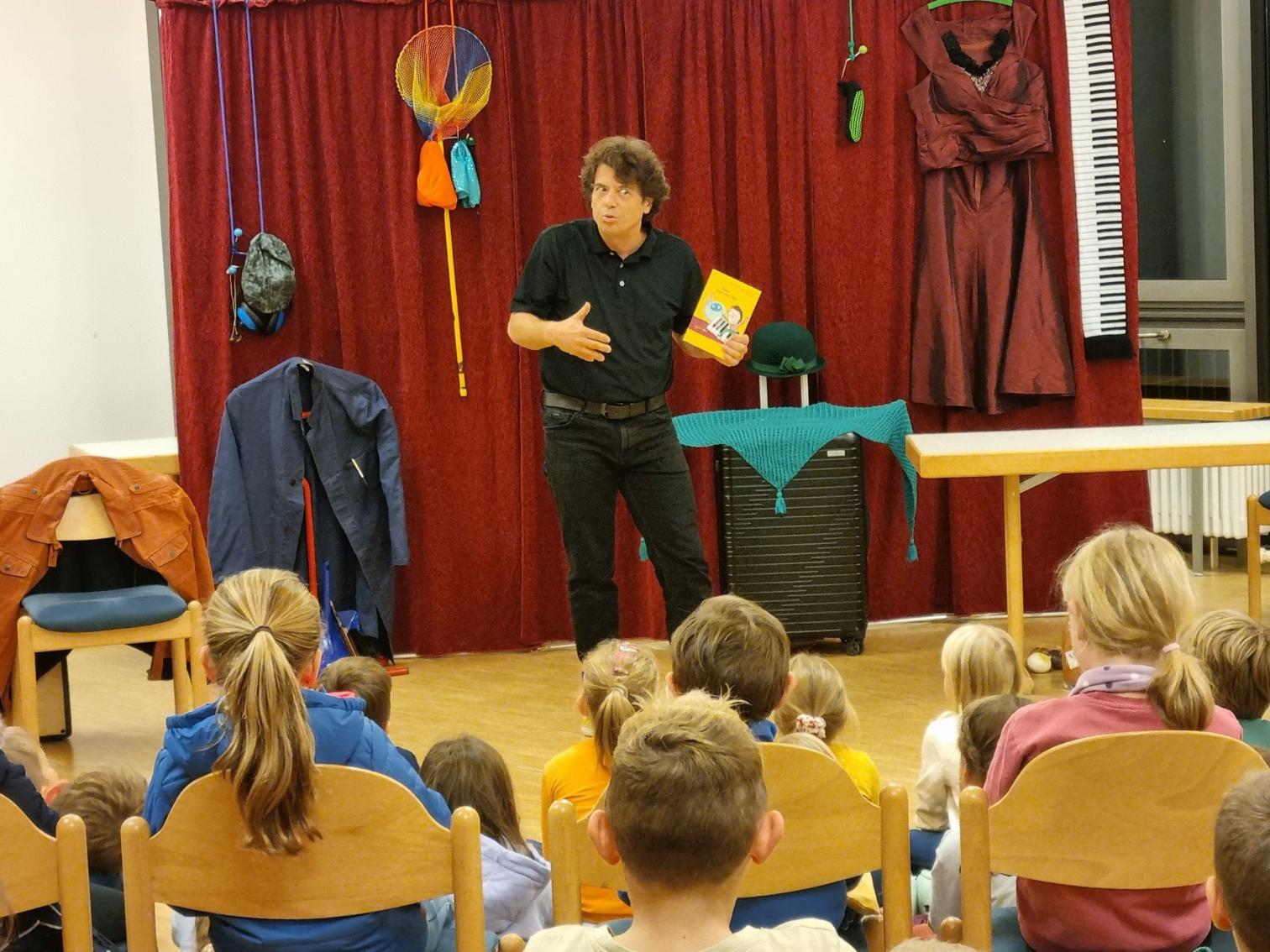 Die Kinder lernen die Geschichte von Theo kennen. Gleich wird Michael Hain sich in Theo verwandeln (c) Bücherei St. Sophia/Willi Weiers