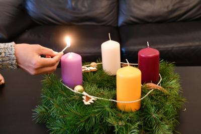 Die erste Kerze am Adventskranz wird angezündet