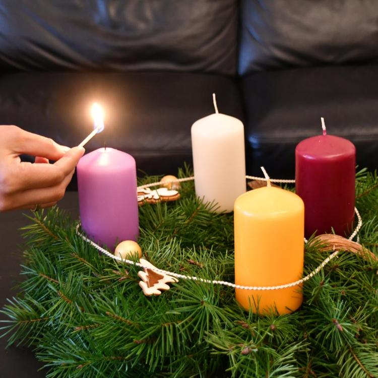 Die erste Kerze am Adventskranz wird angezündet
