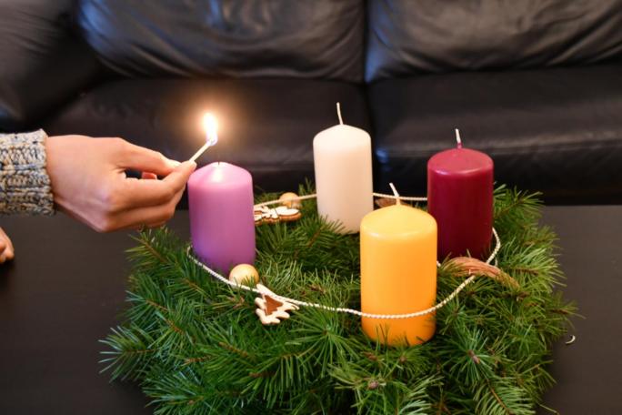 Die erste Kerze am Adventskranz wird angezündet