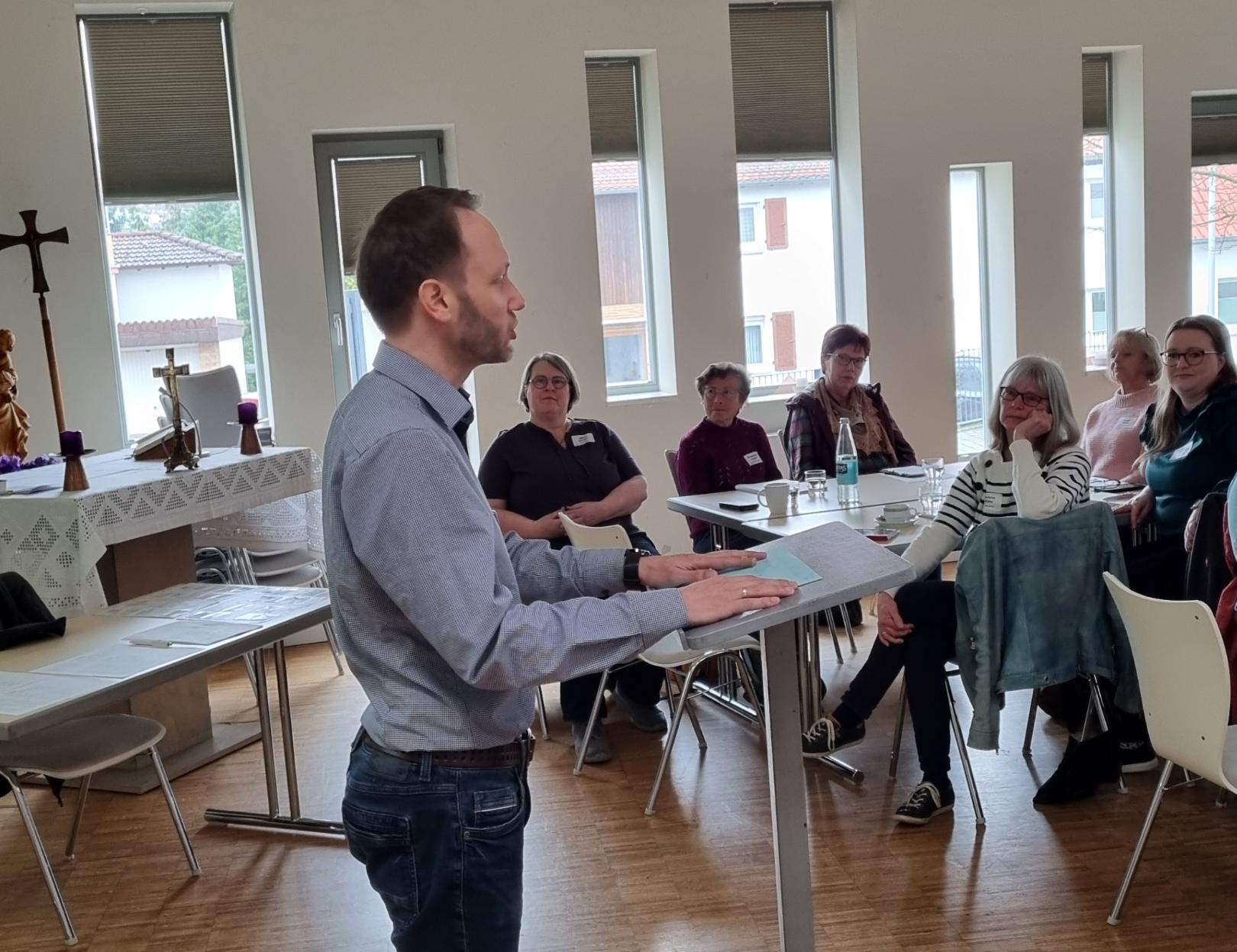 Marcel Schneider, Referent der Fachstelle für Büchereiarbeit während der Begrüßung am Ambo. Der Saal dient kurzfristig als Ausweichraum für Gottesdienste. (c) Fachstelle für Kath. Büchereiarbeit Mainz/WW