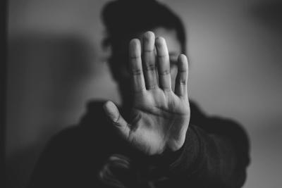 Frau streckt ihre linke Hand als Stopzeichen nach vorne. Gesicht ist nicht zu erkennen (schwarz-weiß)