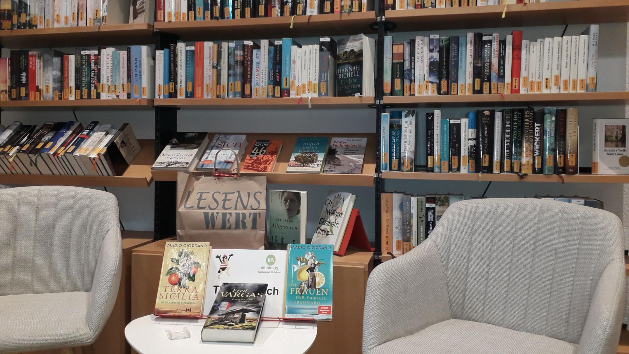 Zwei Sessel mit kleinem Tisch dazwischen vor einem Bücherregal