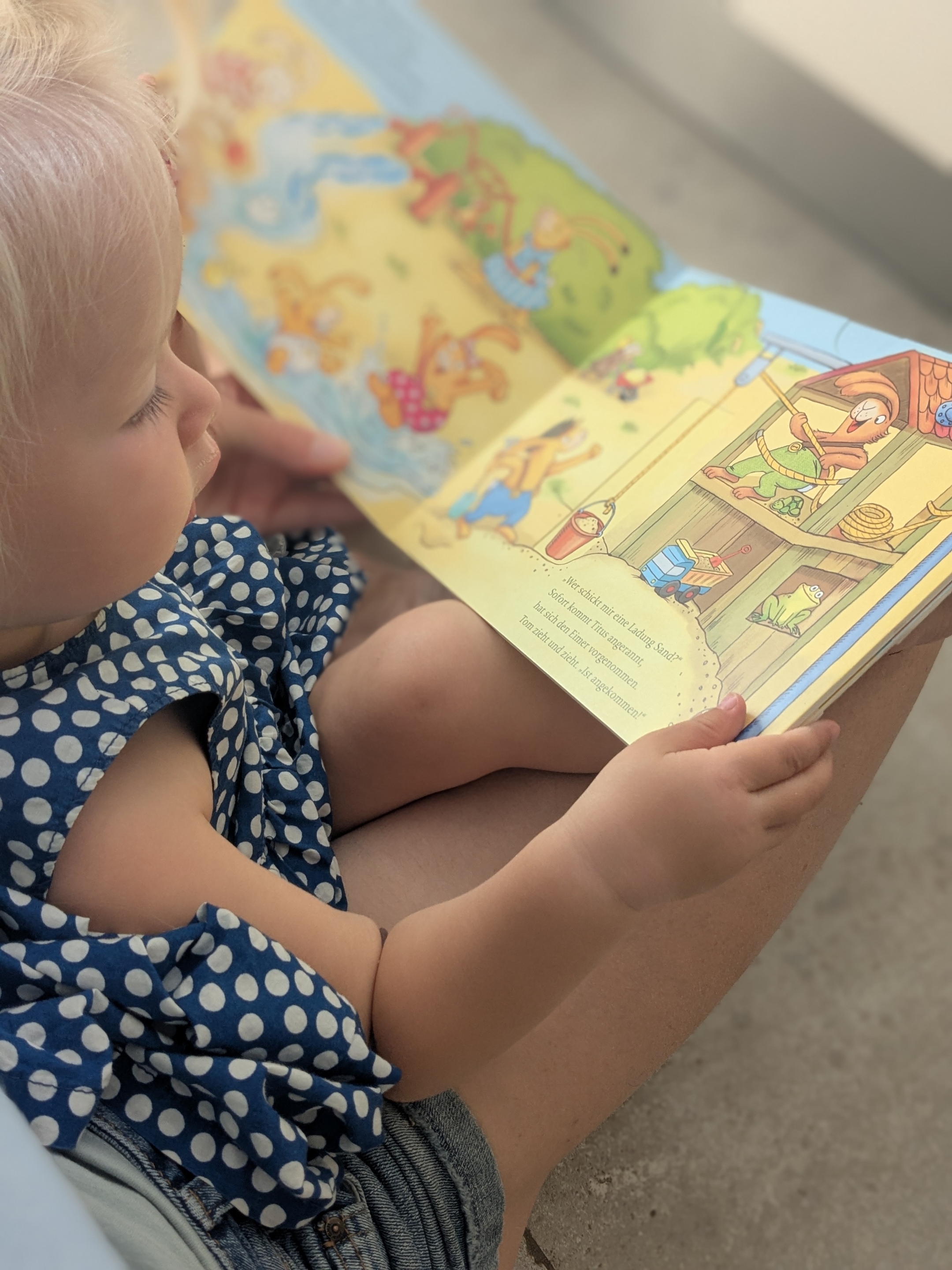 Kind und erwachsene Person mit Bilderbuch in der Hand