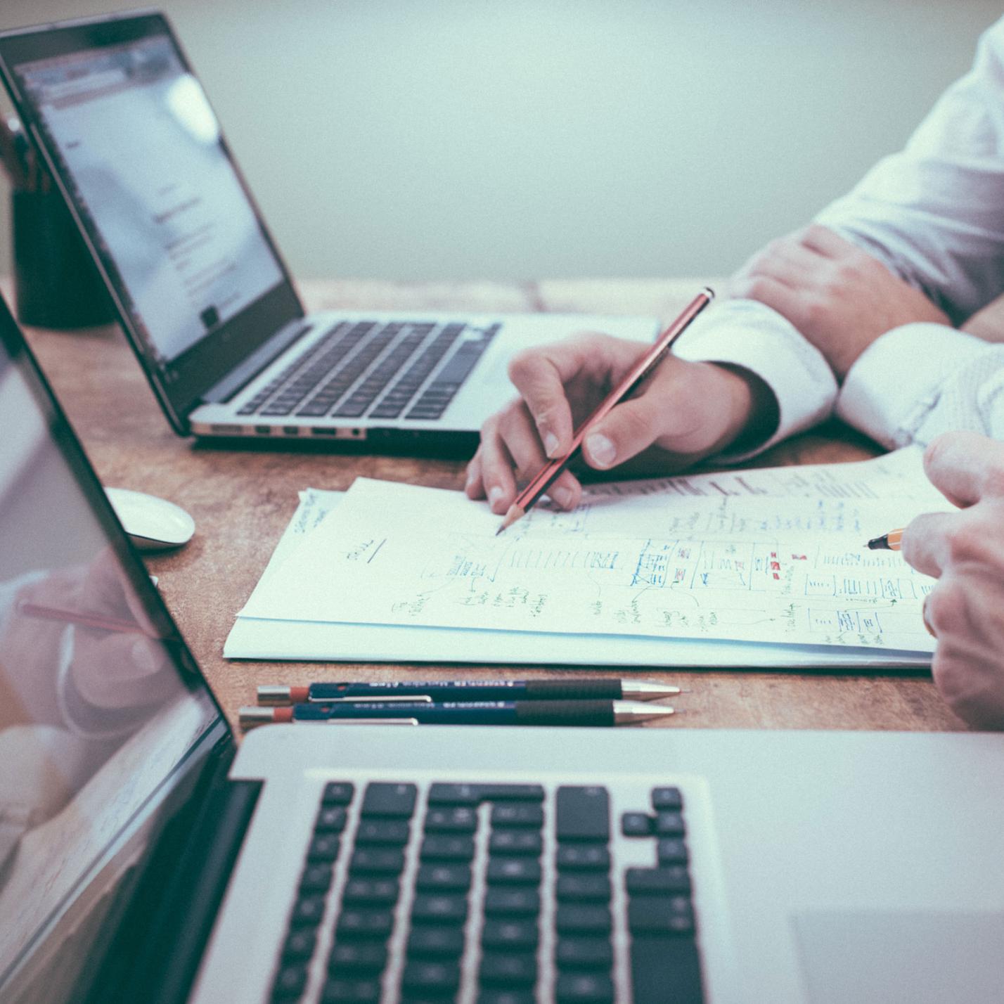 Arbeitstisch mit Laptops und Rechenskizzen