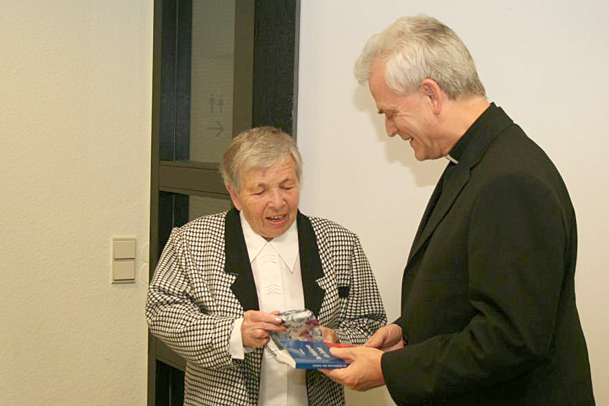 Ruta Wermuth überreicht Weihbischof Guballa ein Exemplar ihres Buches 