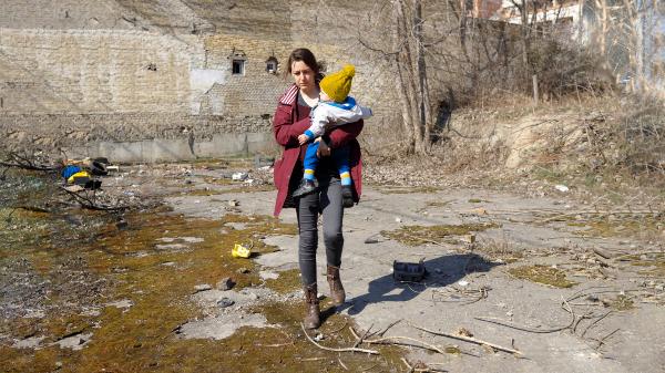 A parent and her child walking among the ruins