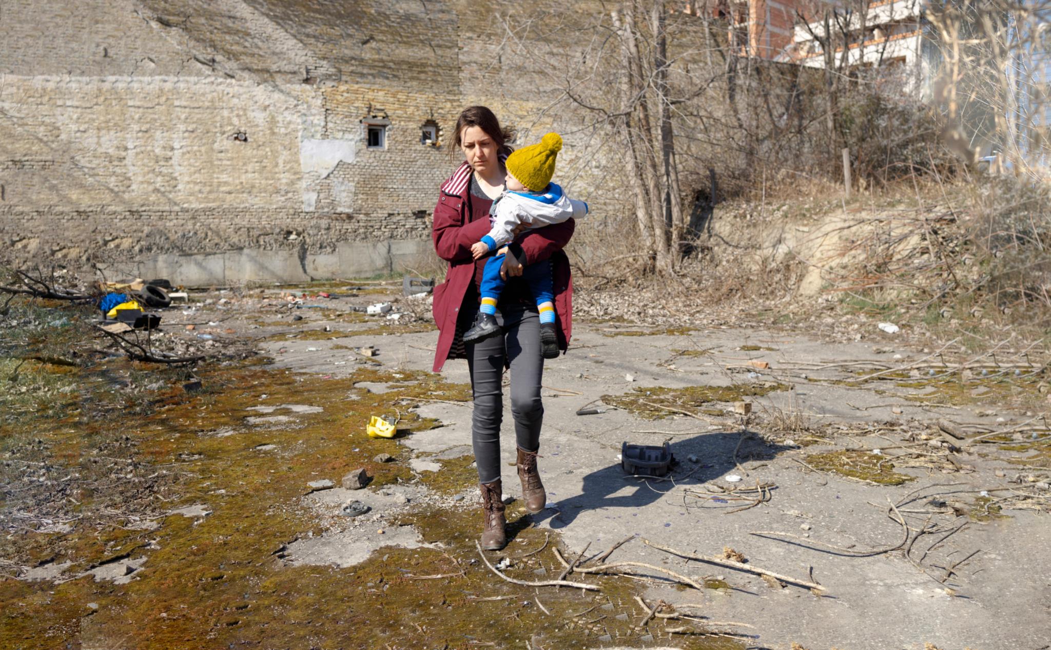 A parent and her child walking among the ruins