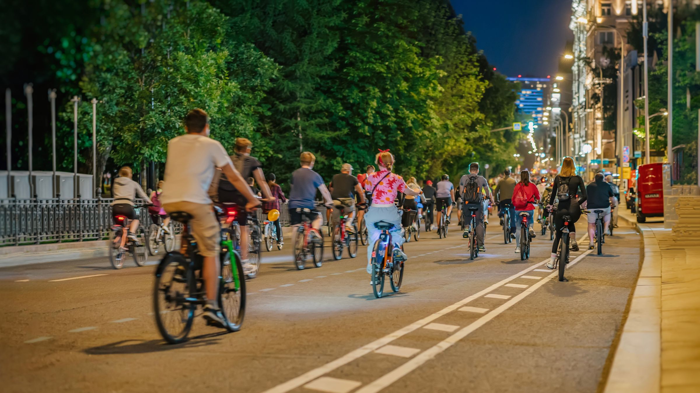 Viele Radfahrer radeln über die ganze Straßer verteilt durch die abendliche Stadt mit Ansicht von hinten