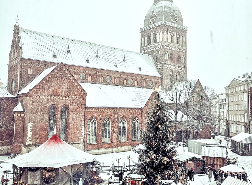 Kirche im Winter mit Weihnachtsmarktständen (c) unsplash