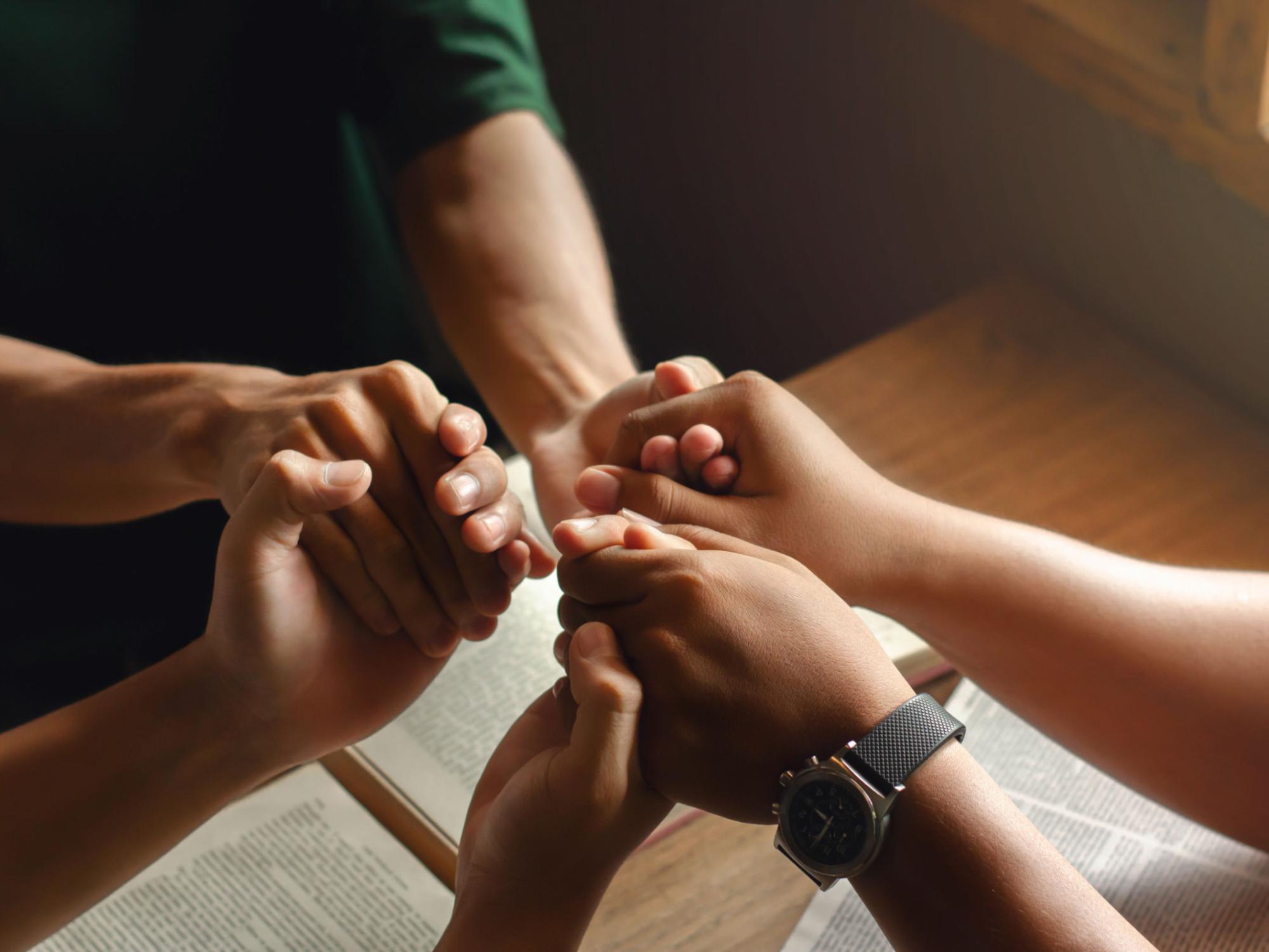 Hände drei junger Menschen die sich im Kreis an den Händen halten