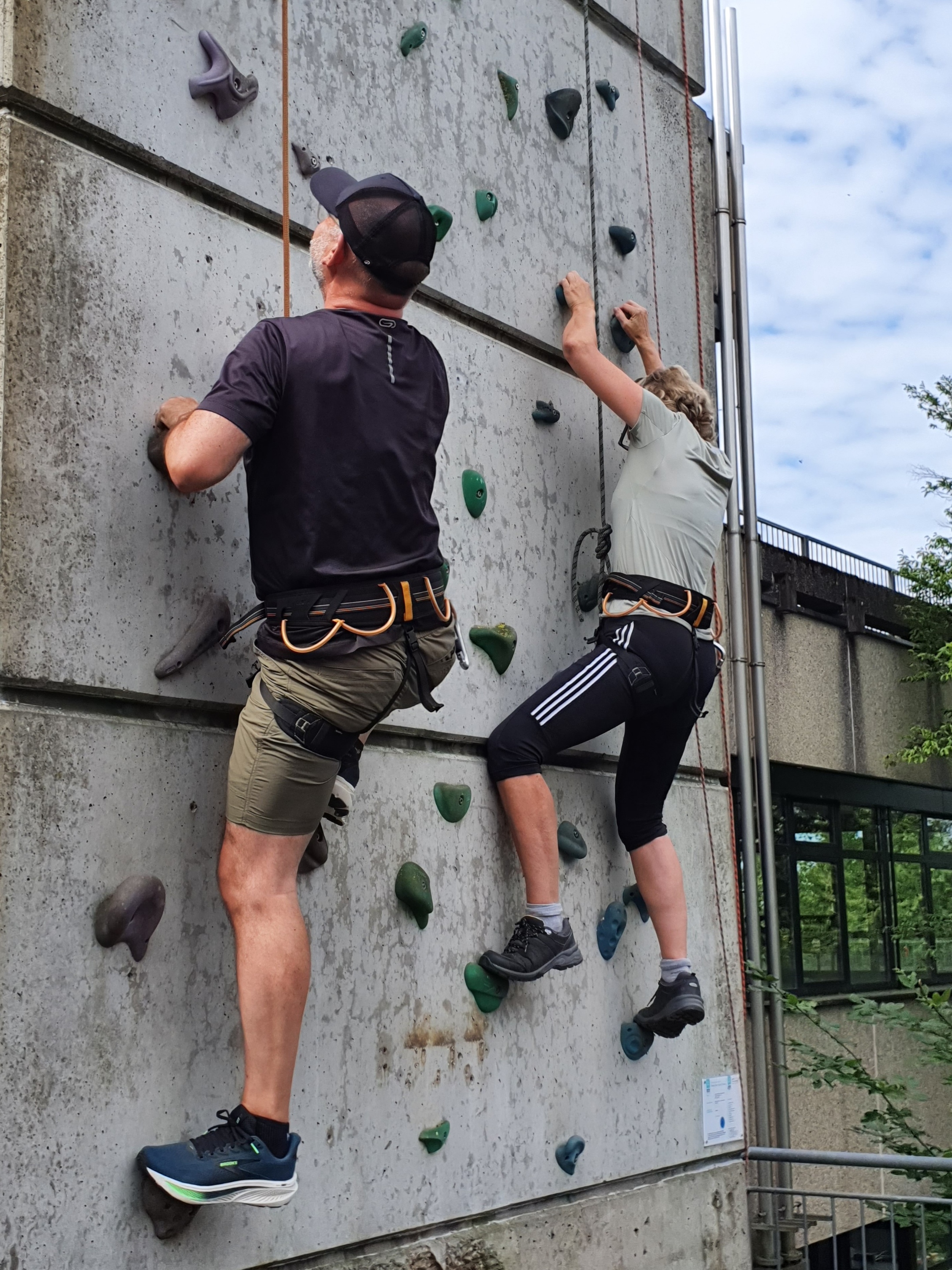 2 Menschen klettern parallel an einer künstlichen Kletterwand