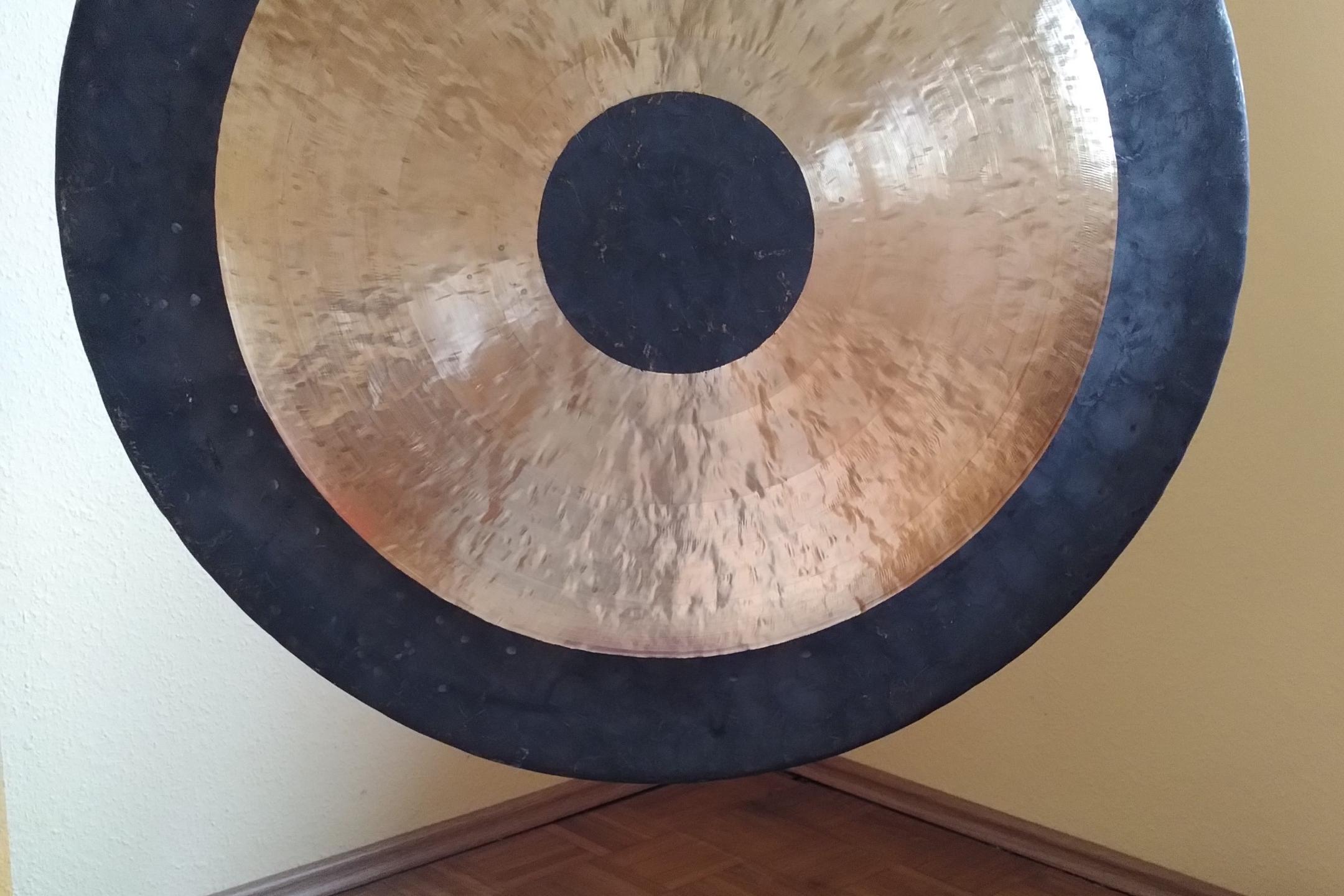 Ein Gong hängt in einer Ecke, davor liegt ein lila Sitzkissen
