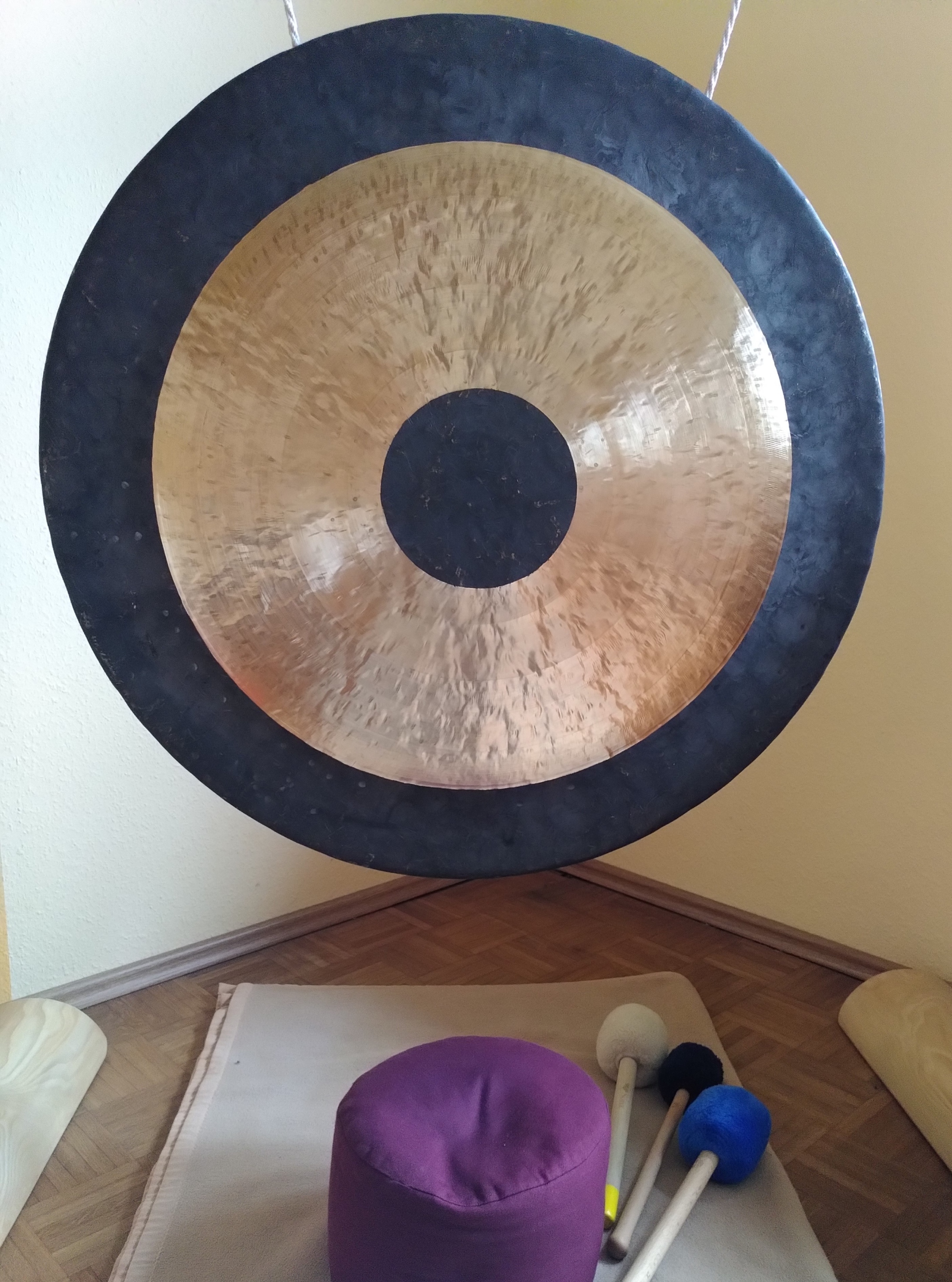 Ein Gong hängt in einer Ecke, davor liegt ein lila Sitzkissen