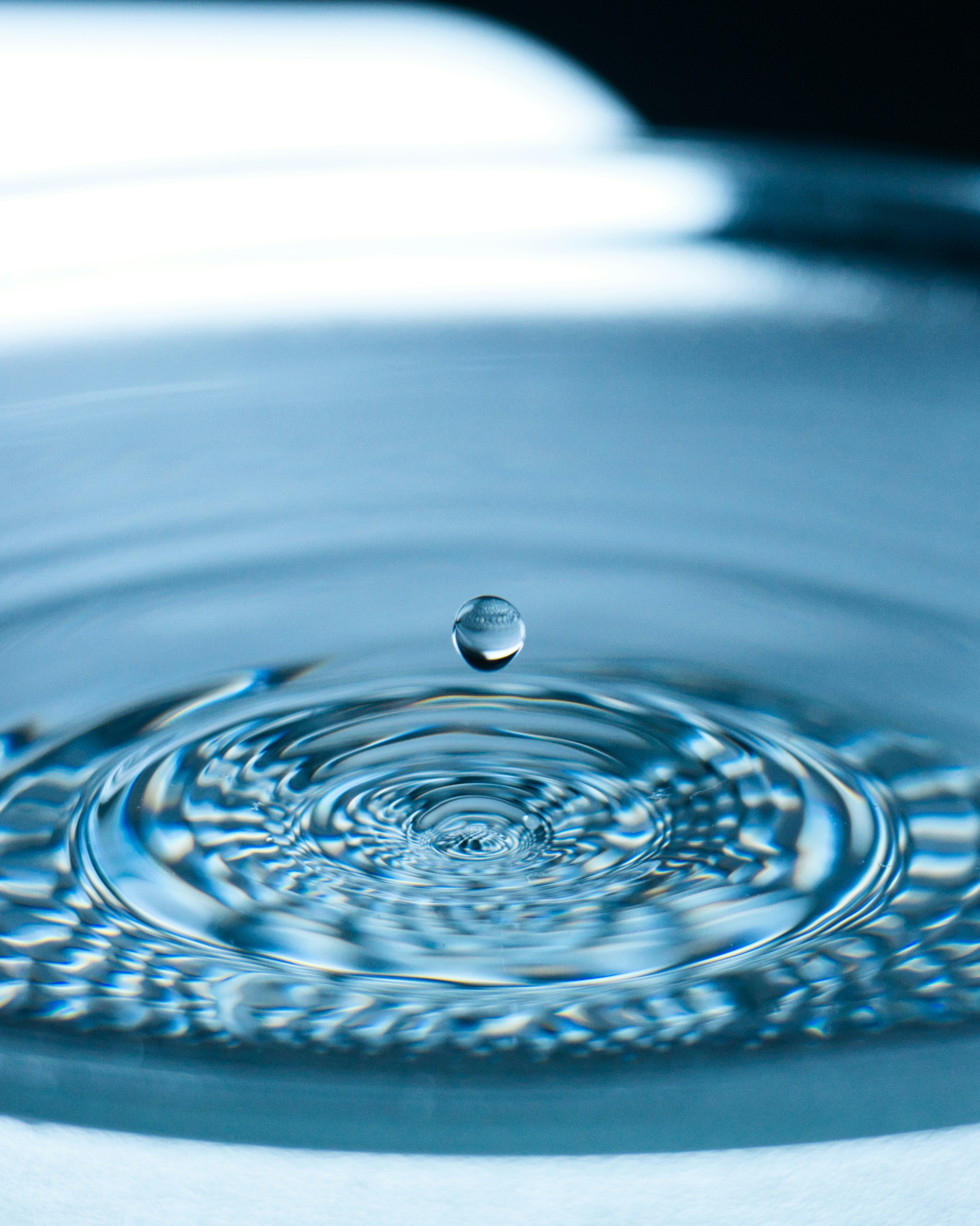 Ein Wassertropen tropft in eine Wasserfläche
