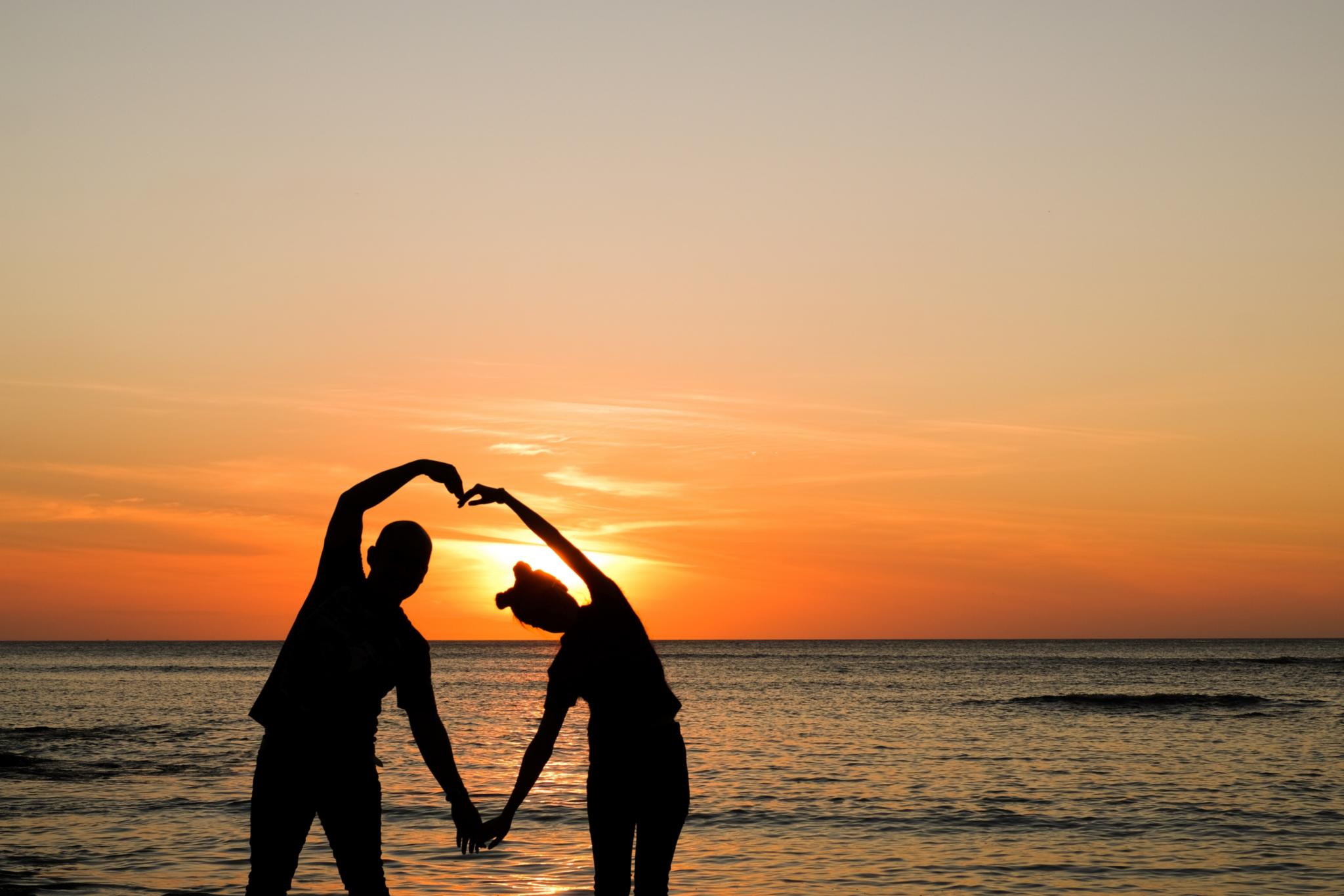 Paar am Strand, die Hände formen ein Herz