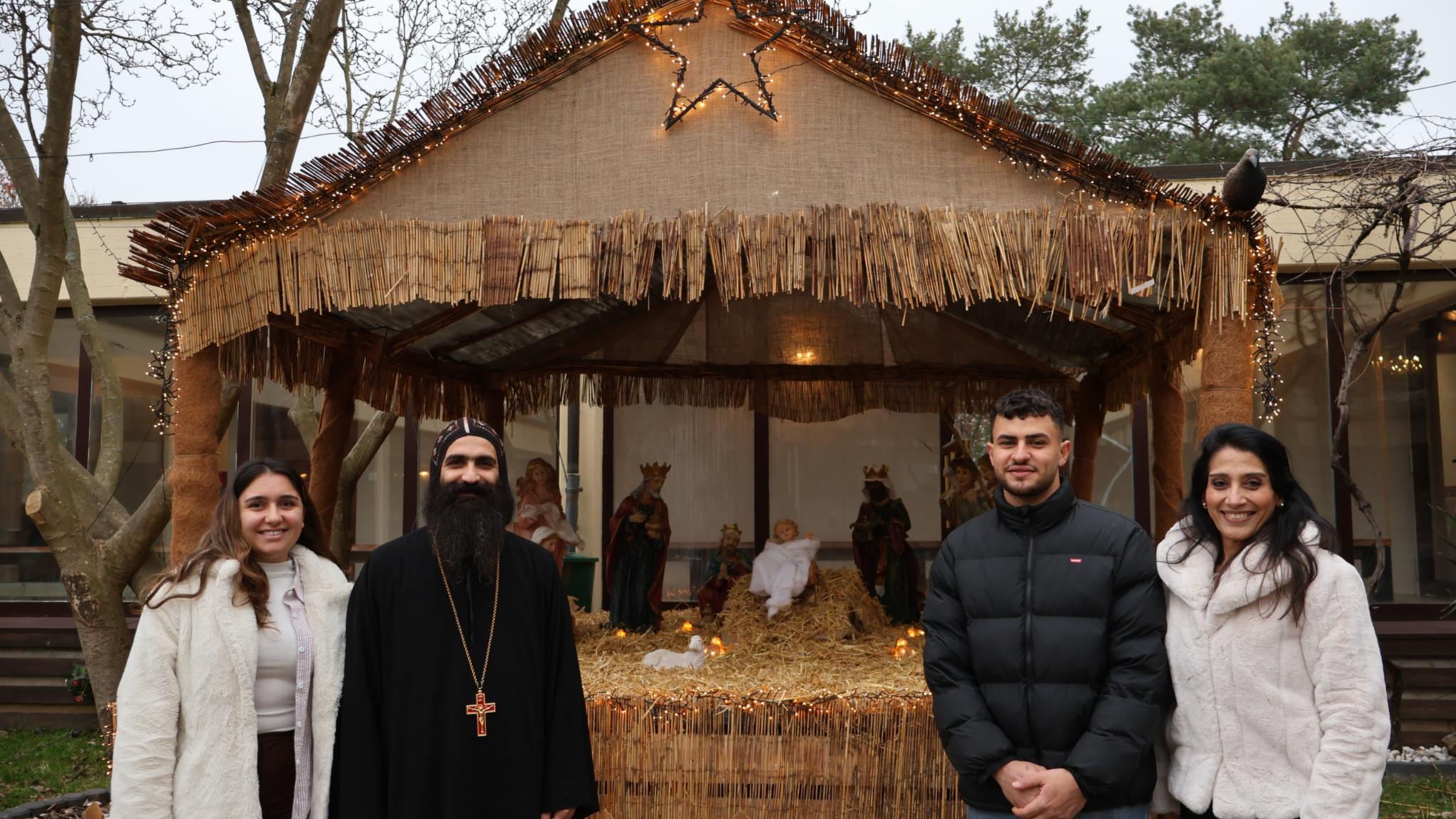 Vater Johannes St. Antonius und Cherine Azer (rechts) mit Gemeindemitgliedern an der Krippe im Hof.