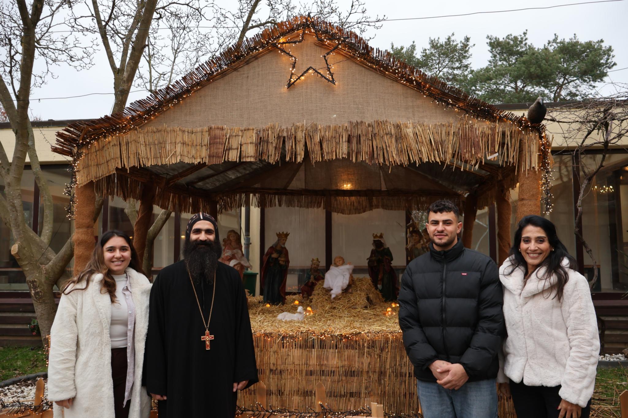 Vater Johannes St. Antonius und Cherine Azer (rechts) mit Gemeindemitgliedern an der Krippe im Hof.