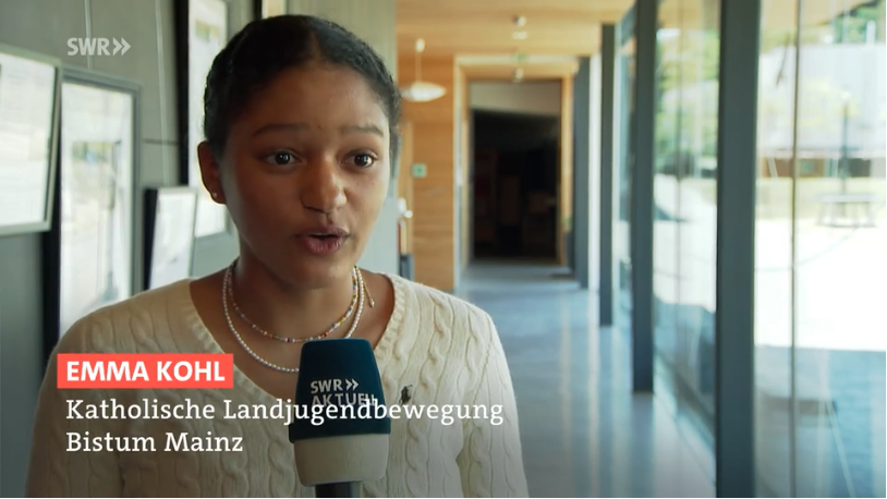 die junge Diözesanleiterin der Katholischen Landjugendbewegung im lichtdurchfluteten Flur des Mainzer Jugendhauses mit Mikrophon