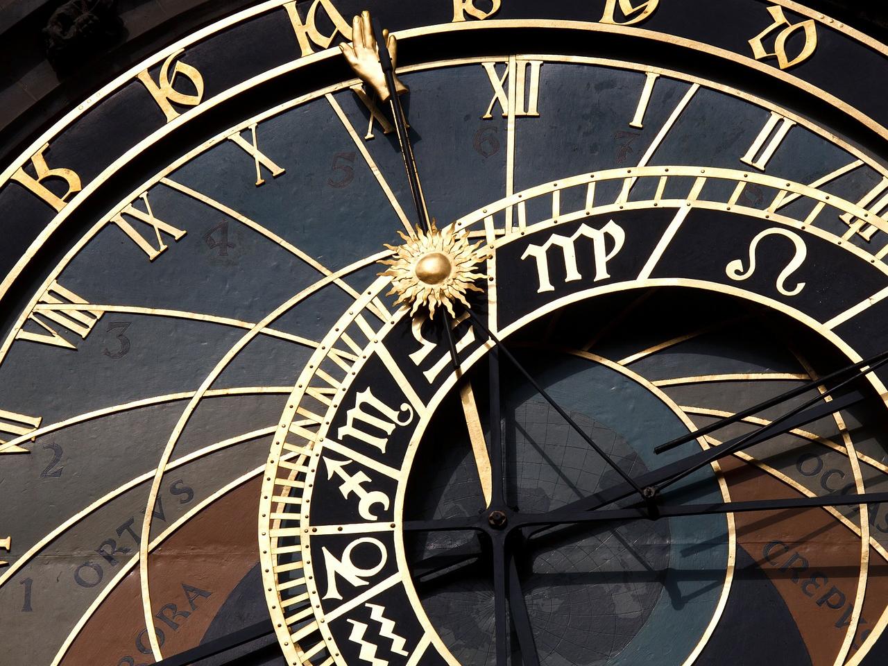 Astronomische Uhr mit goldenen Ziffern und Zeigern auf dunklem Hintergrund