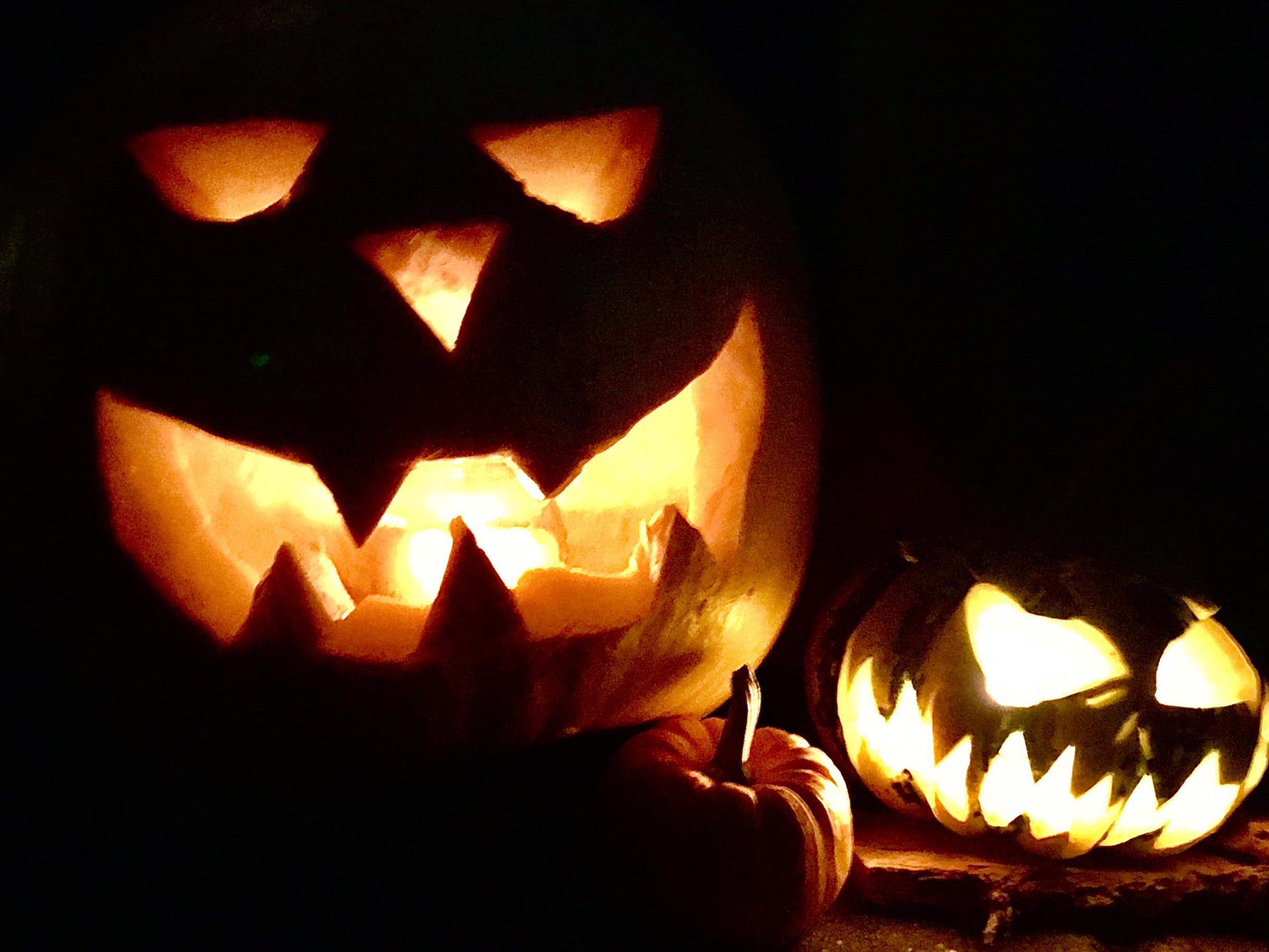 Gruselige, geschnitzte Halloweenkürbisse mit Kerzenlicht im Innern.