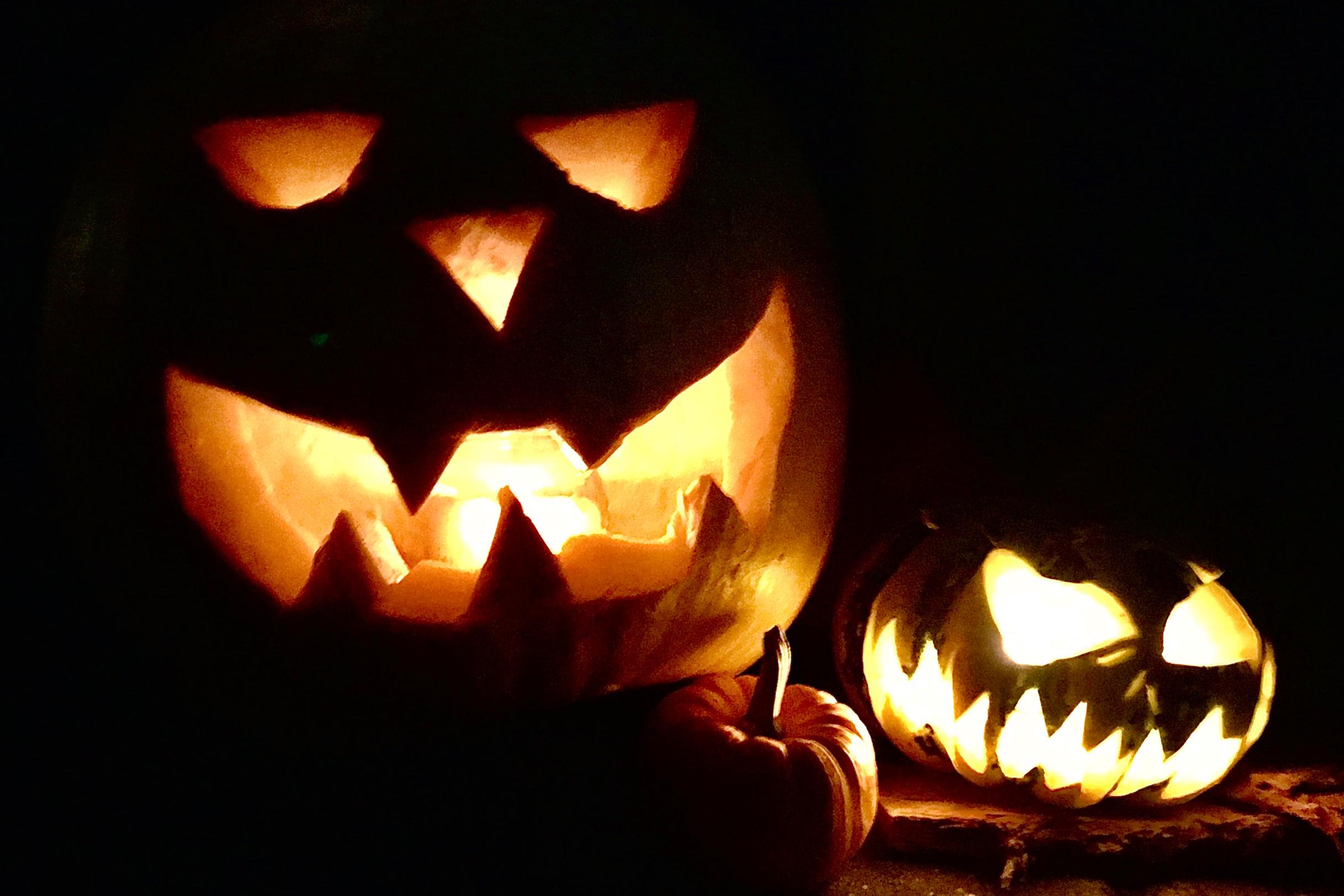 Gruselige, geschnitzte Halloweenkürbisse mit Kerzenlicht im Innern.