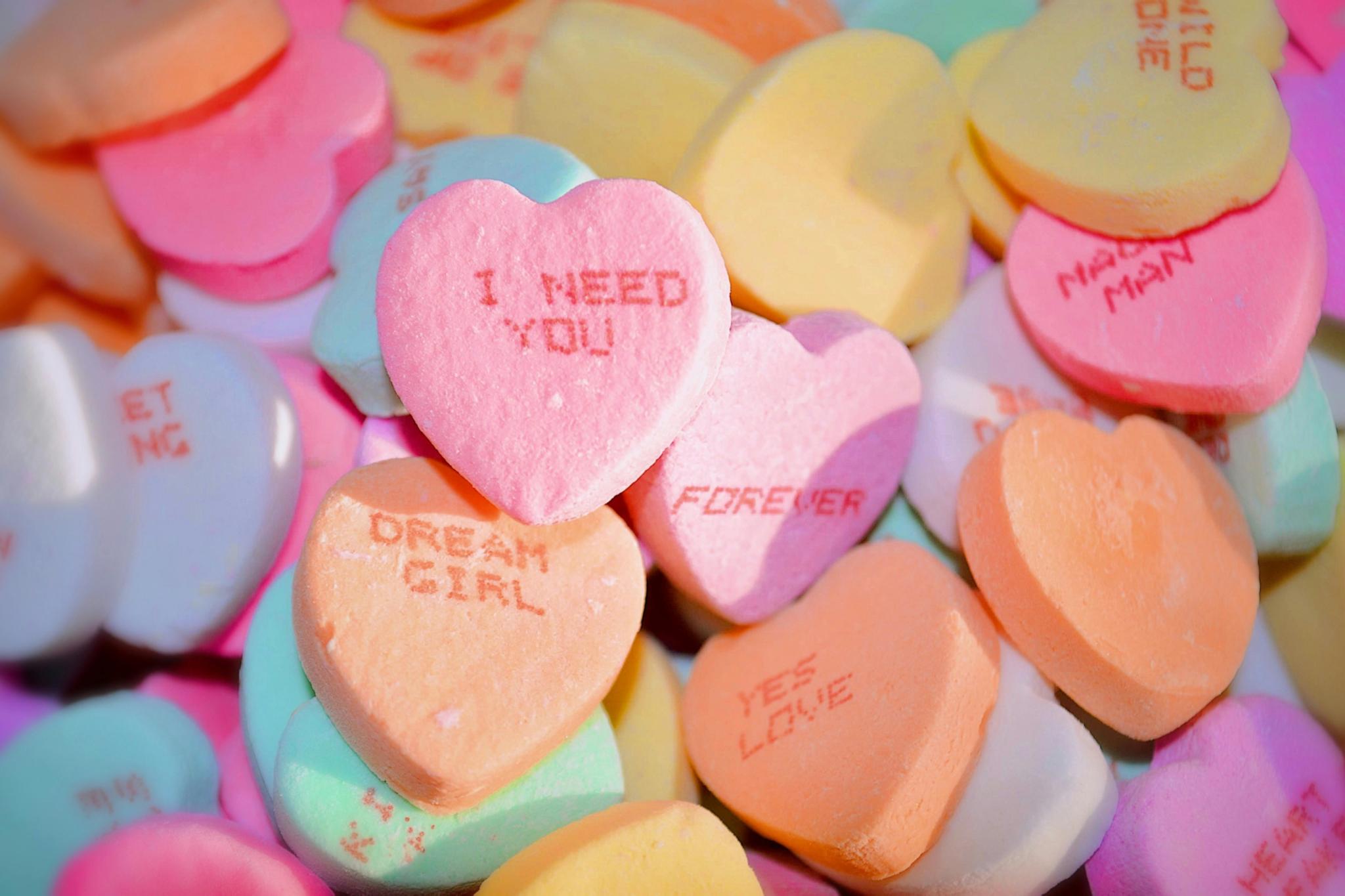 Bonbons in Herzform, auf dem Sprüche stehen, wie z. B. 'I need you'