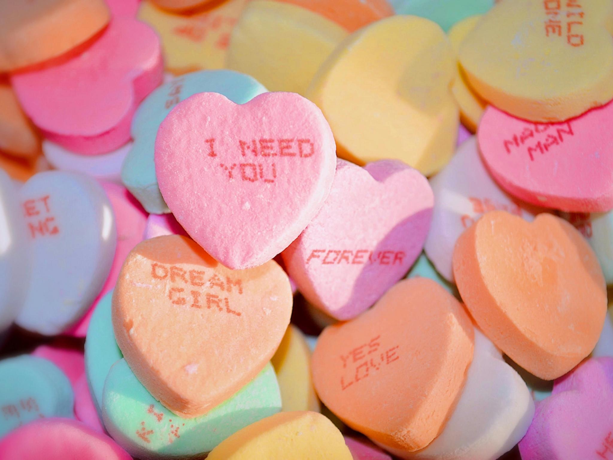 Bonbons in Herzform, auf dem Sprüche stehen, wie z. B. 'I need you'