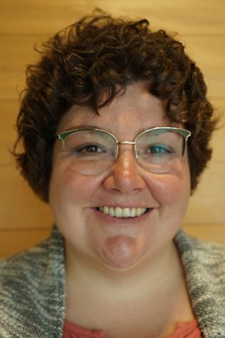 Frau mit Brille, die in die Kammera lächelt