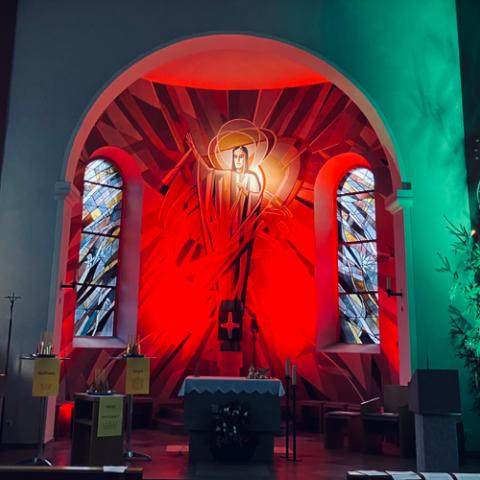 In einer Kriche. Im Altarraum ist an der Wand Jesus aufgemalt.