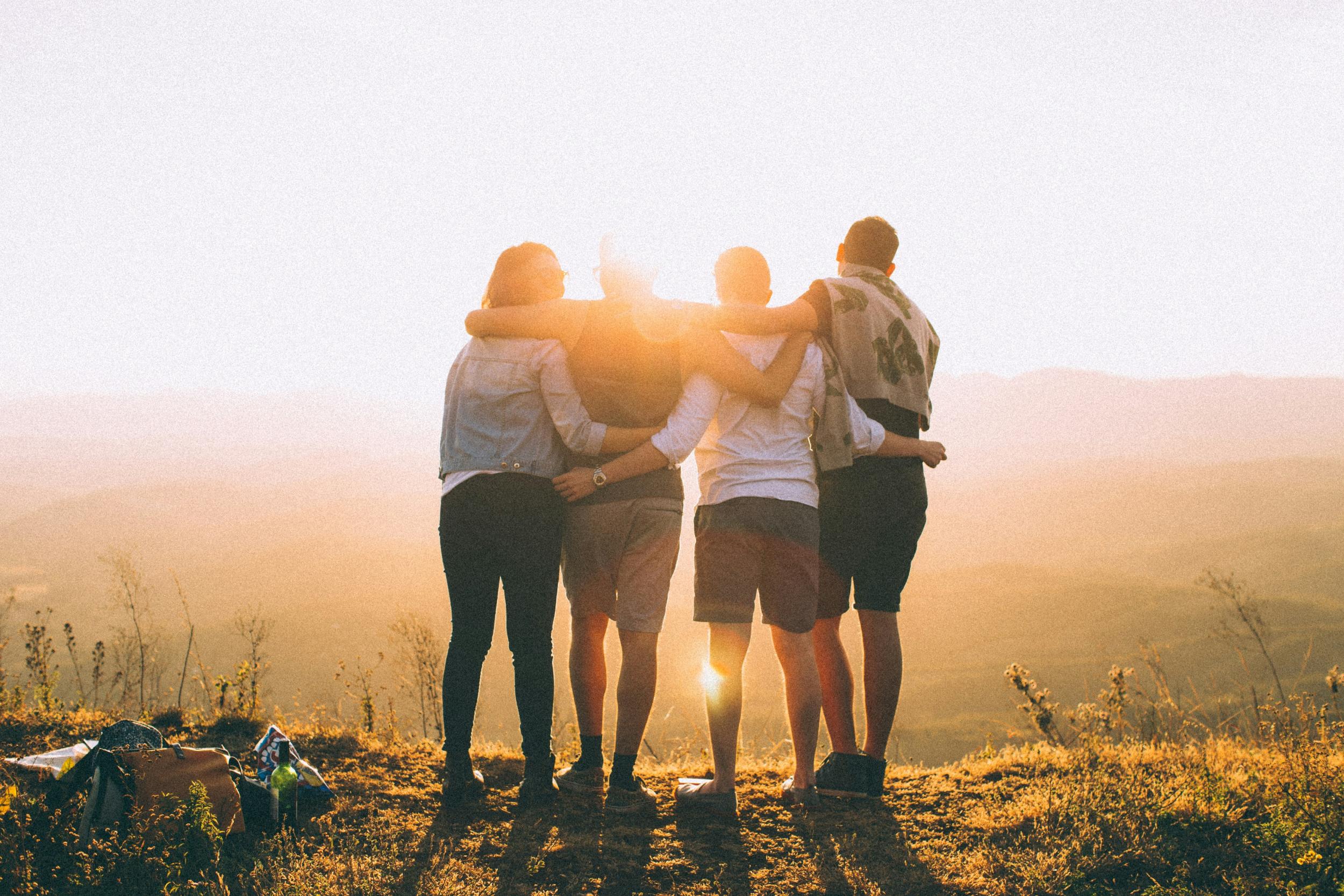 Vier Jugendliche von hinten schauen in den Sonnenuntergang