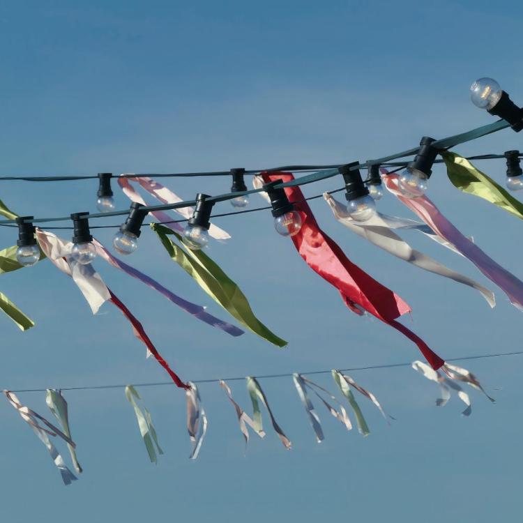 Bunte Stoffbänder wehen vor einem klaren, blauen Sommerhimmel