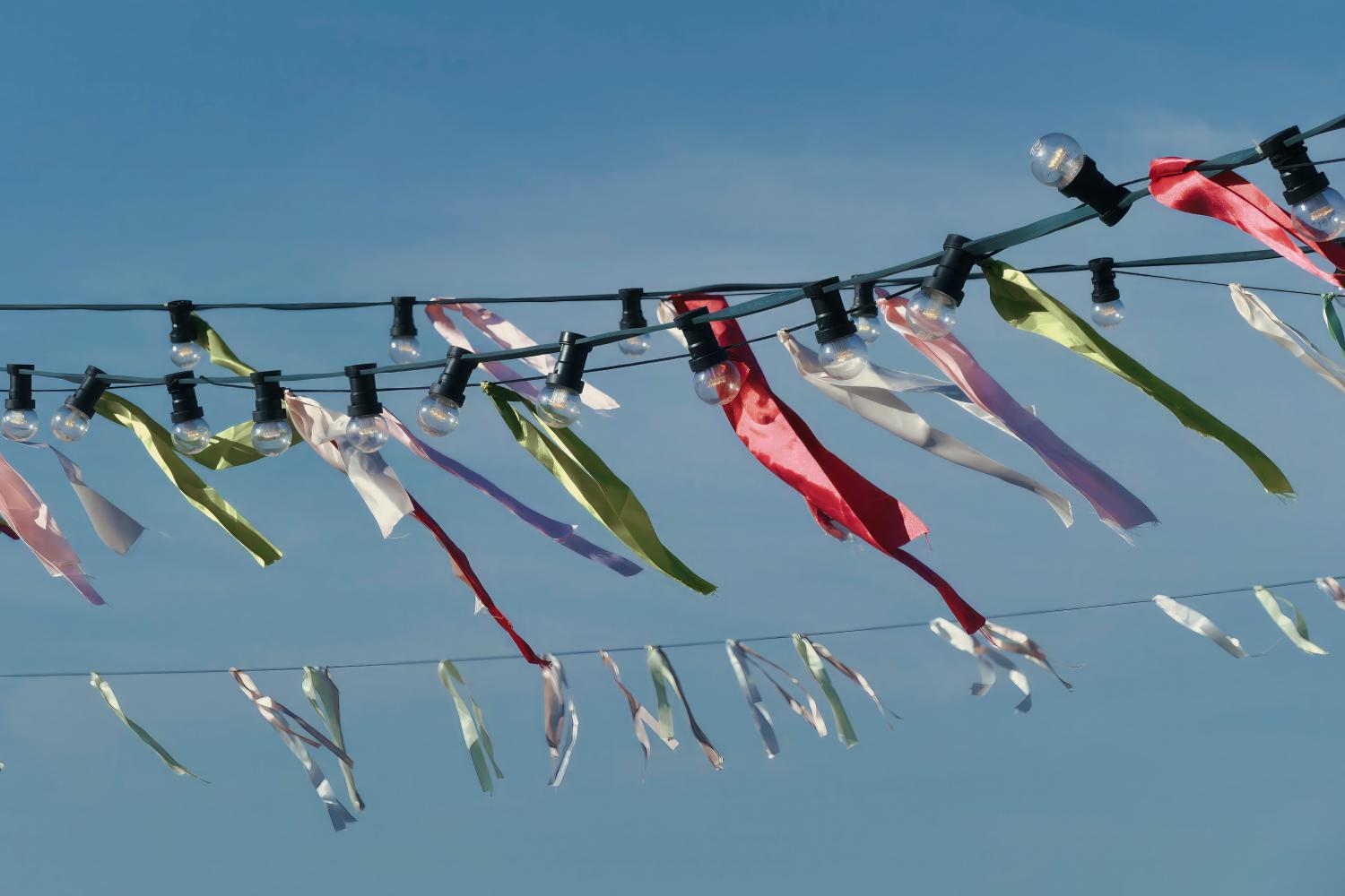 Bunte Stoffbänder wehen vor einem klaren, blauen Sommerhimmel