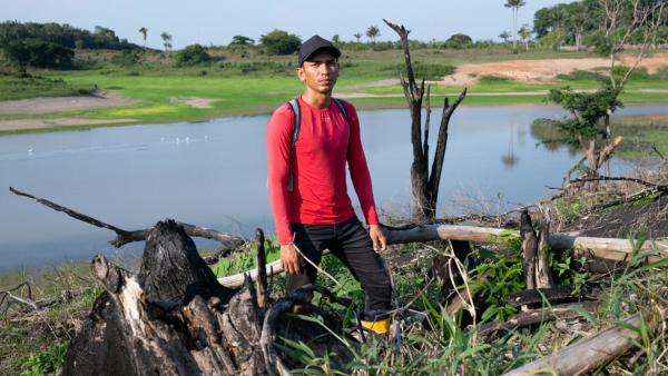 Gabriel da Silva (26) an einem abgebrannten Baum, Brandrodung in direkter Nachbarschaft der Mura-Gemeinde Lago de Soares