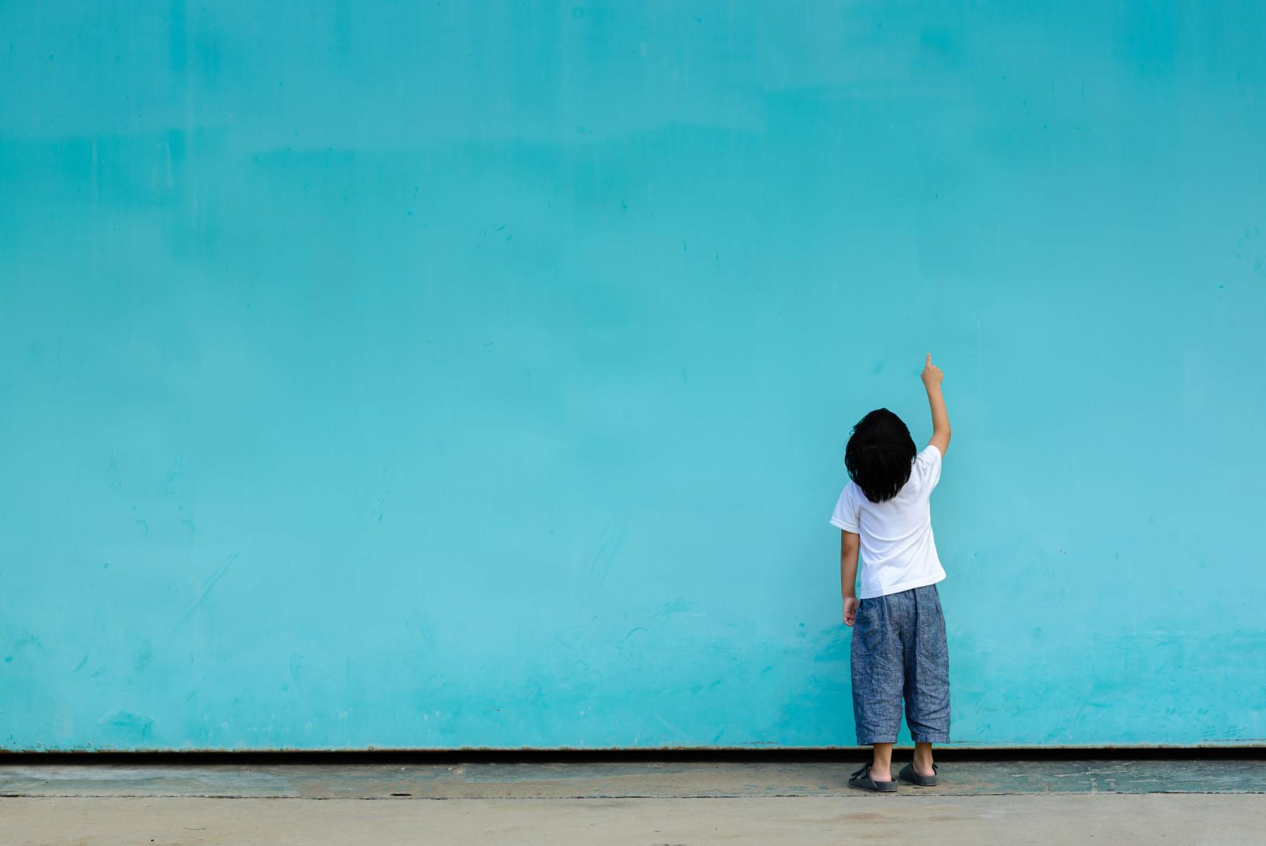 Junge vor türkisfarbener Wand (c) stockbob | stock.adobe.com