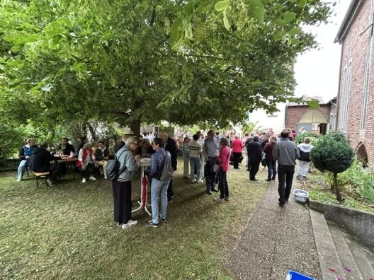 Besucher des Pfarrgruppenfestes sitzen und stehen gemeinsam unter der großen Linde im Pfarrgarten von Christkönig