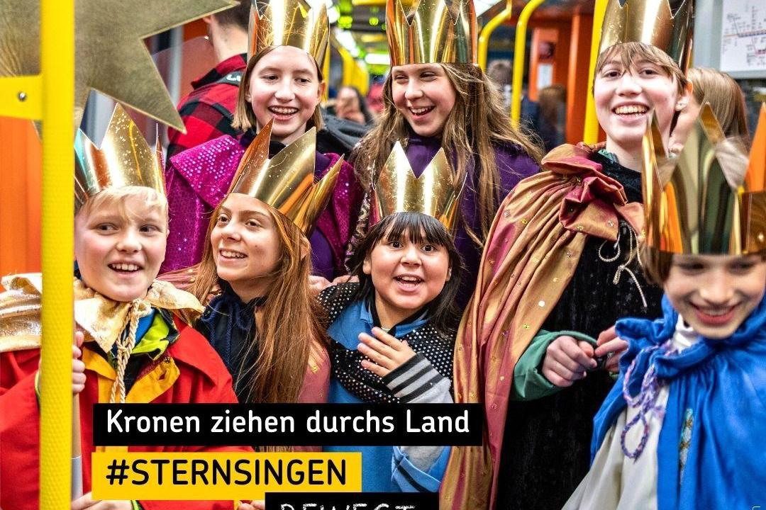 Kinder als Sternsinger in einer Straßenbahn mit Text 'Kronen ziehen durchs Land'