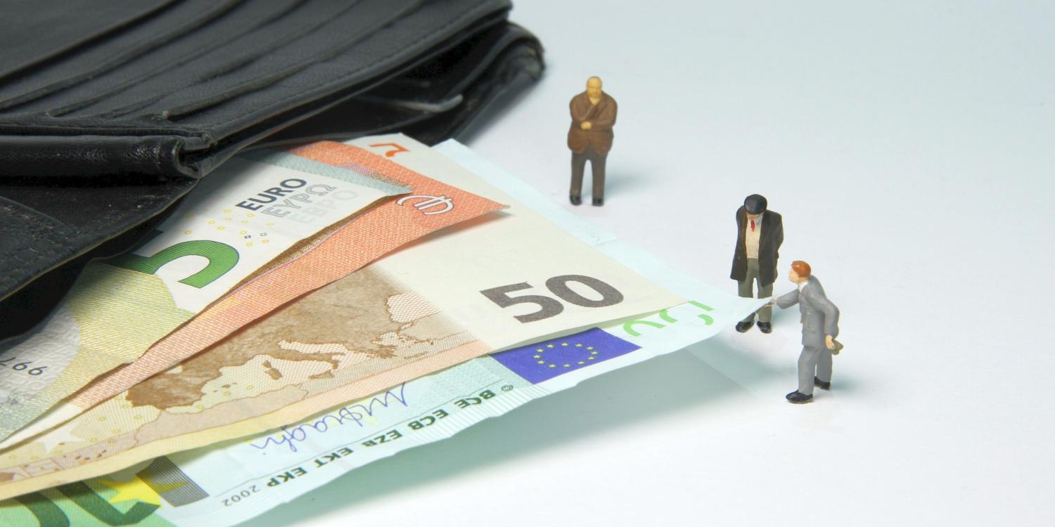 Miniaturfiguren neben Geldscheinen