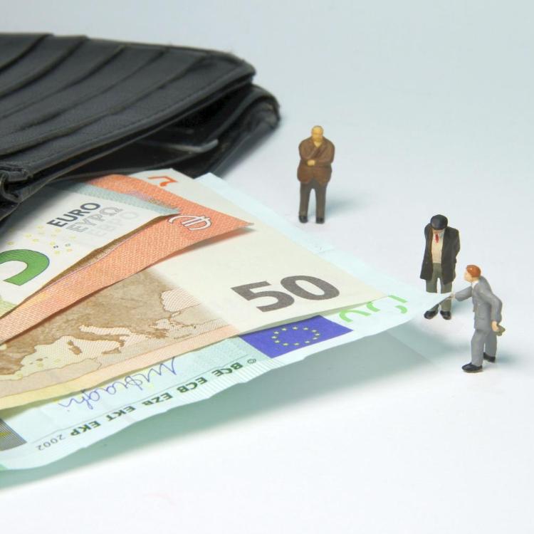Miniaturfiguren neben Geldscheinen