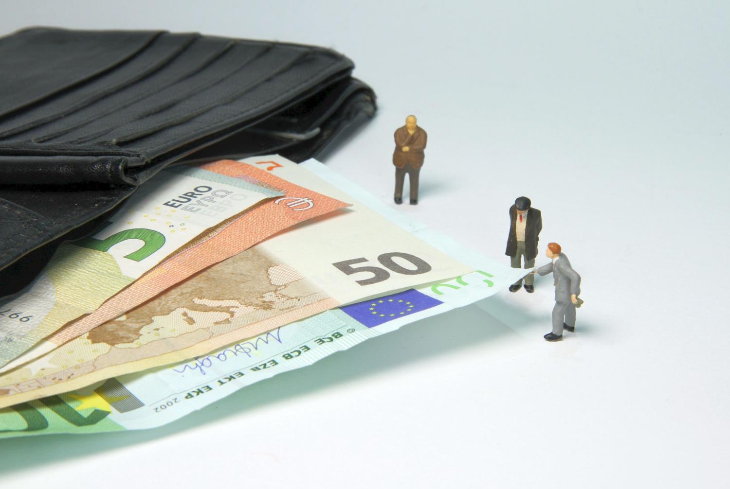 Miniaturfiguren neben Geldscheinen
