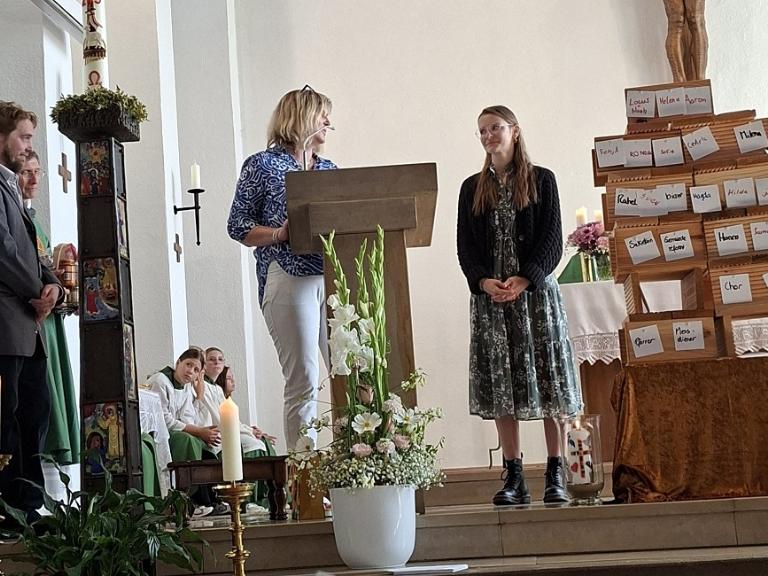 Menschen stehen im Altarraum einer Kirche und begrüßen eine neue Pastoralreferentin.
