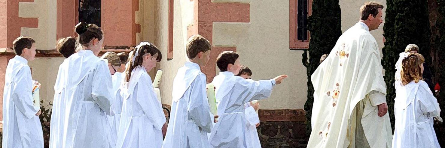 Pfarrer und zehn Kommunionkinder laufen außen an einer Kirche vorbei.