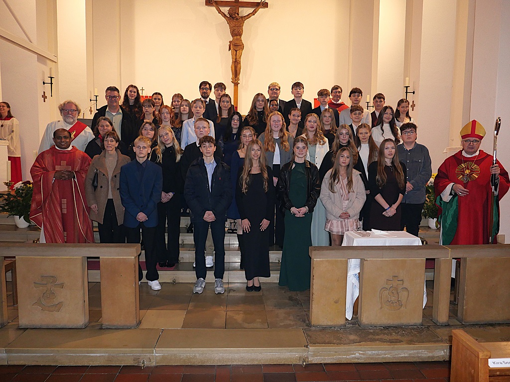 35 Jugendliche in einem Kirchenraum mit Bischof und weiteren Geistlichen und Erwachsenen.